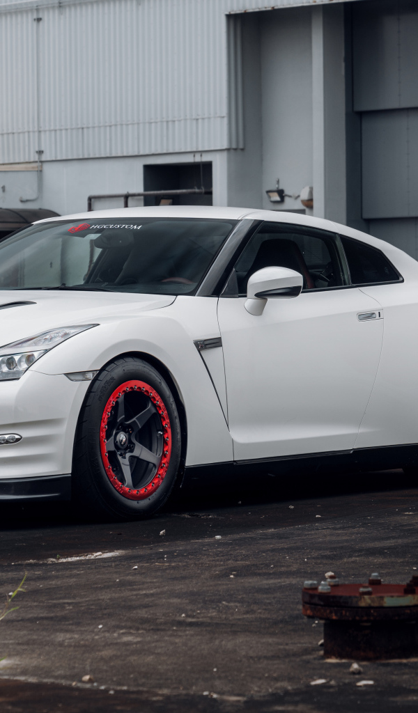 Белый автомобиль Nissan GT-R у гаража