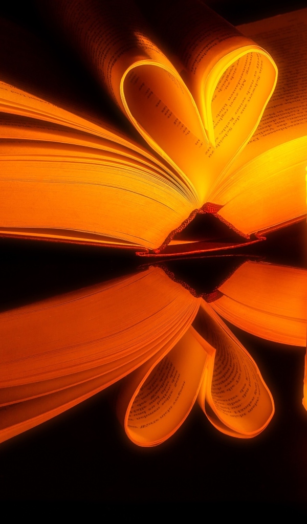 Открытая книга с зажженной свечой отражаются в черной поверхности