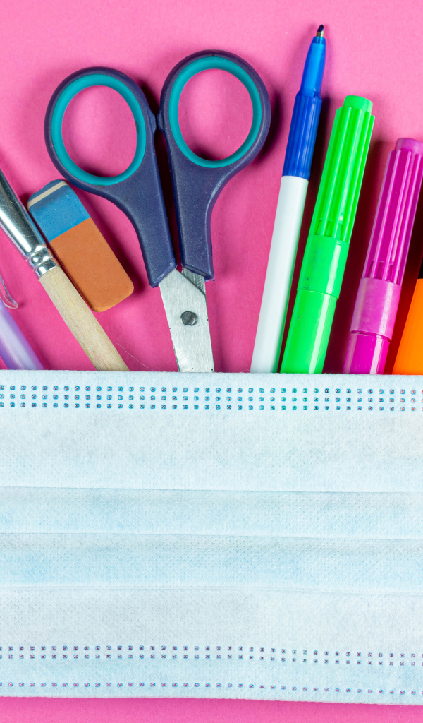 Канцелярские предметы и медицинская маска на розовом фоне