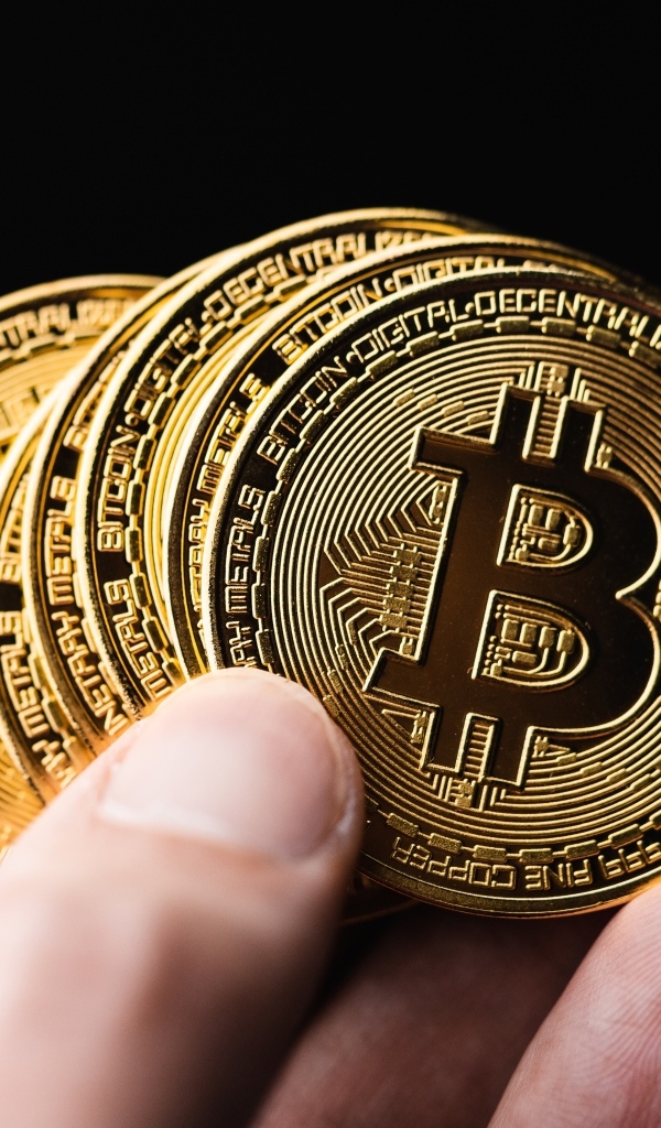 Монеты биткоин в руке на черном фоне