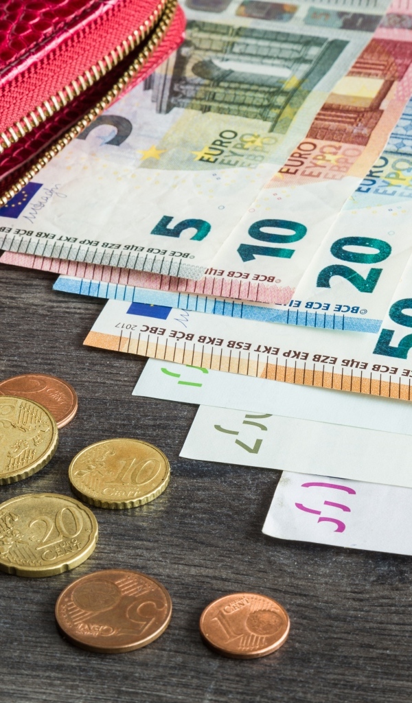 Купюры евро с монетами и кошельком на столе