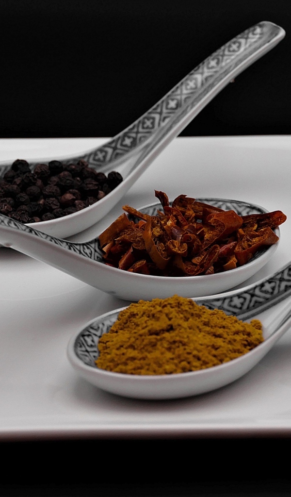 Ароматные специи в ложках на белой тарелке