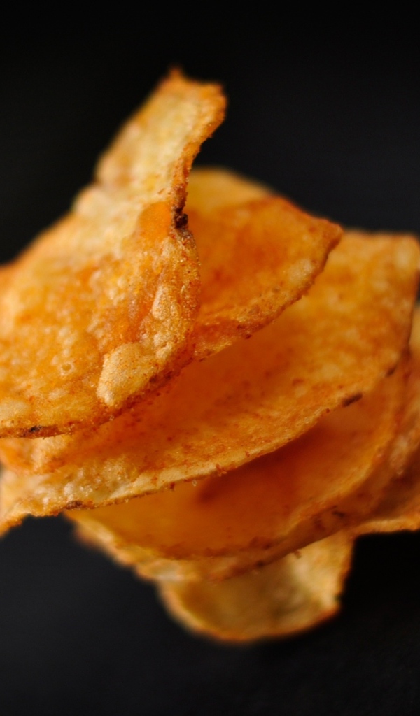 Хрустящие картофельные чипсы на черном фоне