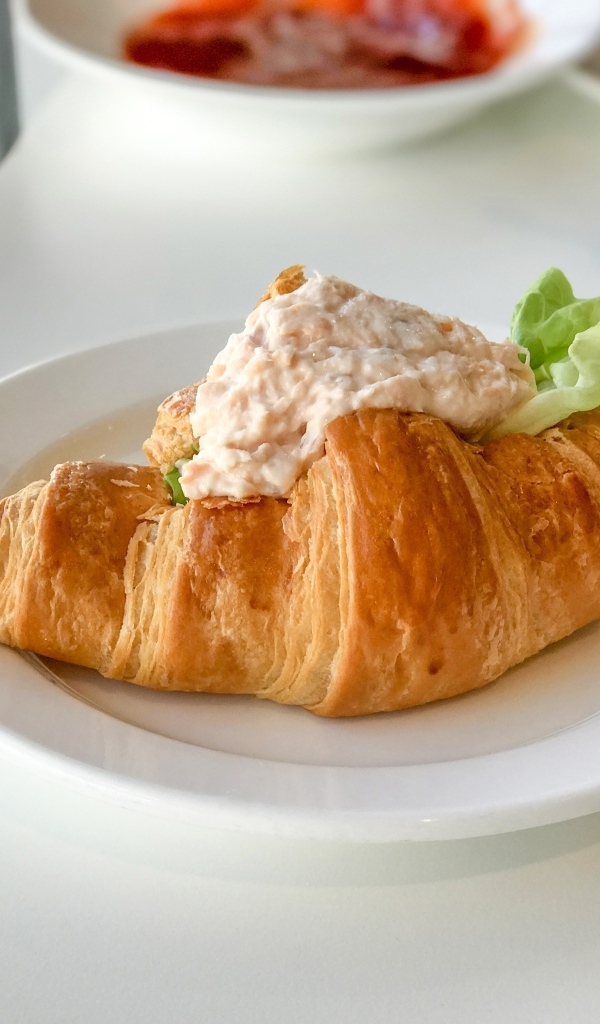 Круассан с начинкой на белой тарелке на завтрак 