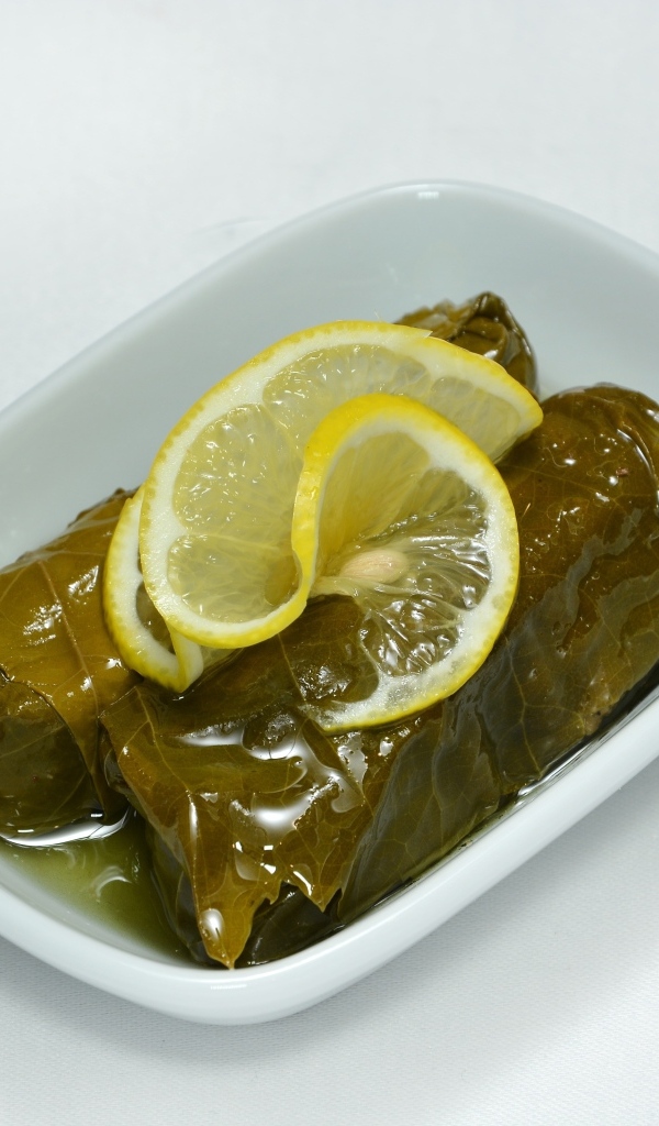 Долма с лимоном с тарелке на сером фоне