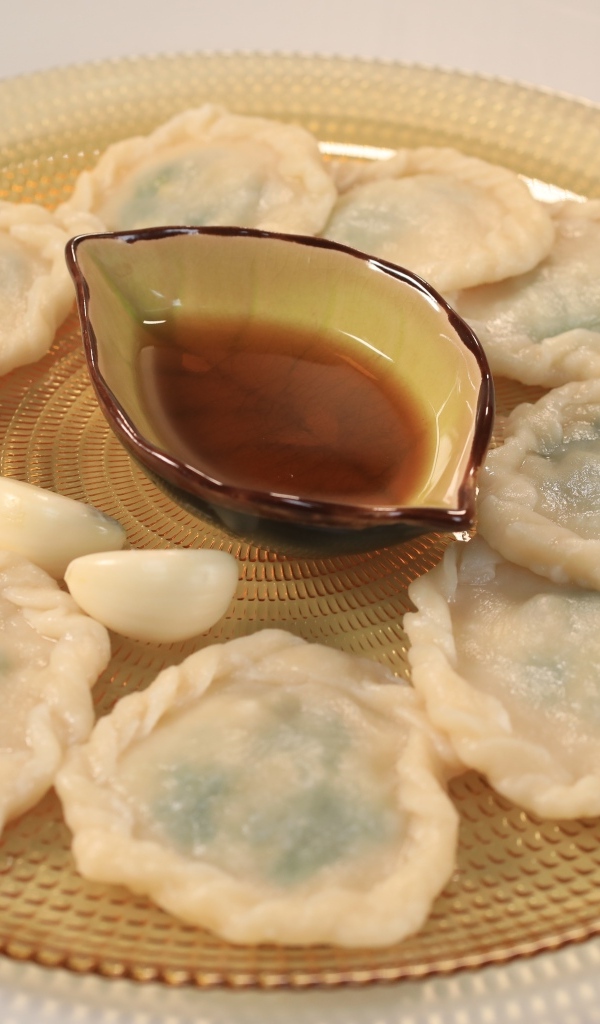 Блюдо дамплинг с соусом и чесноком на тарелке