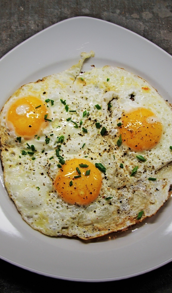 Яичница глазунья в тарелке на сером столе