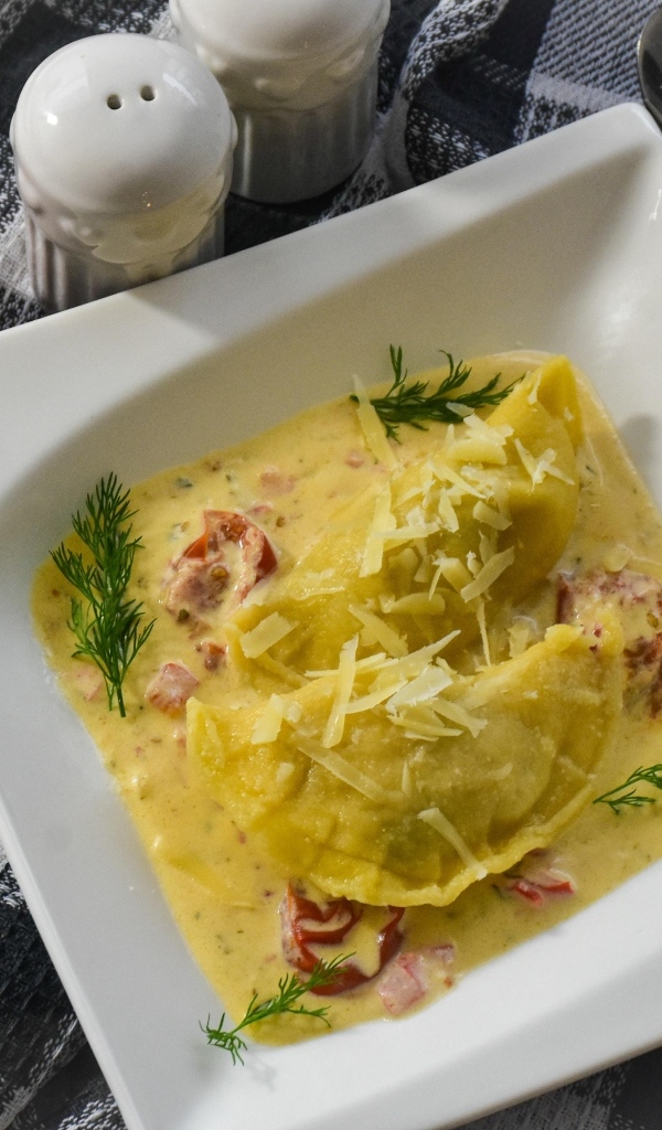 Равиоли с соусе с беконом на тарелке