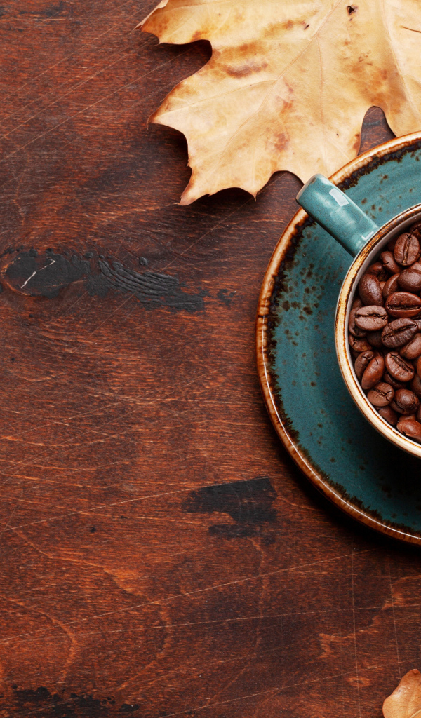 Чашка с кофейными зернами на столе с листьями