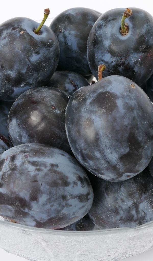 Стеклянная тарелка с вкусными синими сливами