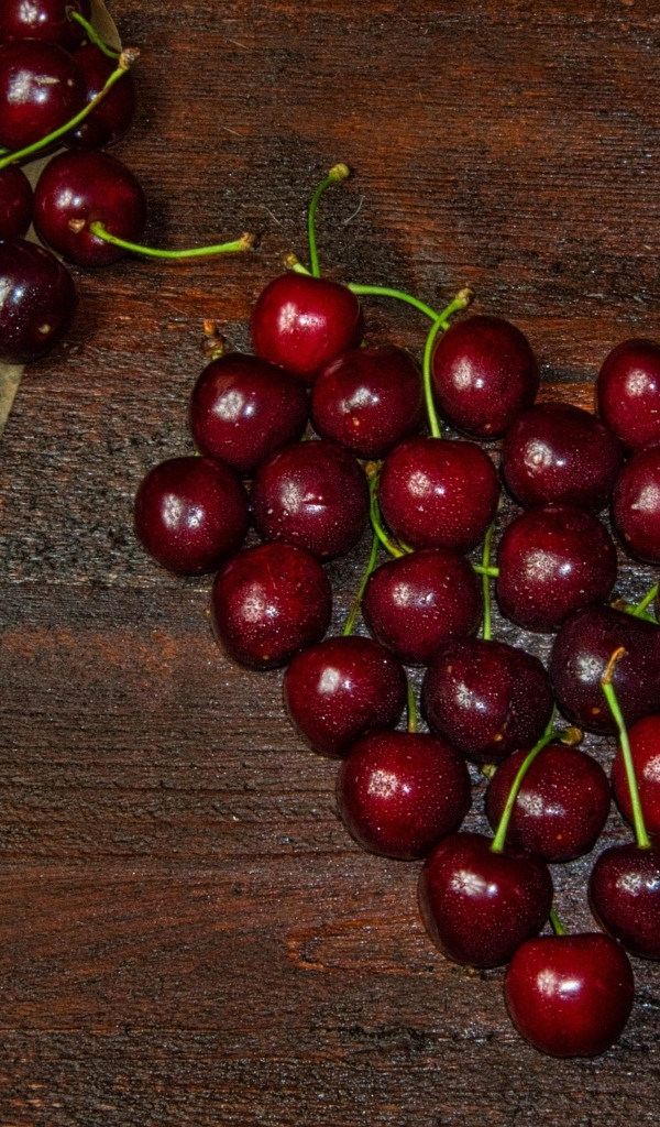 Сердце из спелых ягод черешни на деревянном столе