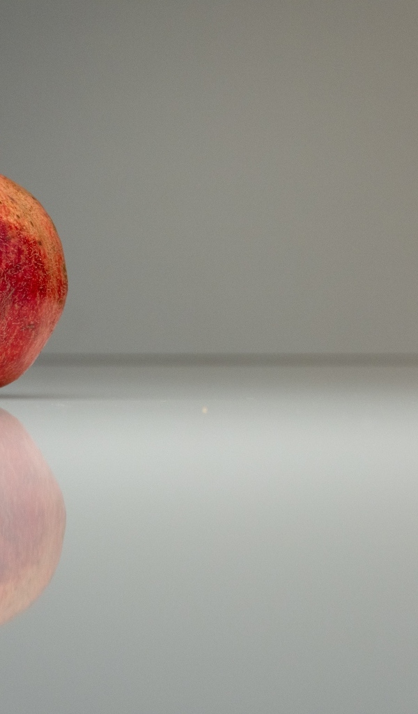 Красный гранат отражается в поверхности на сером фоне