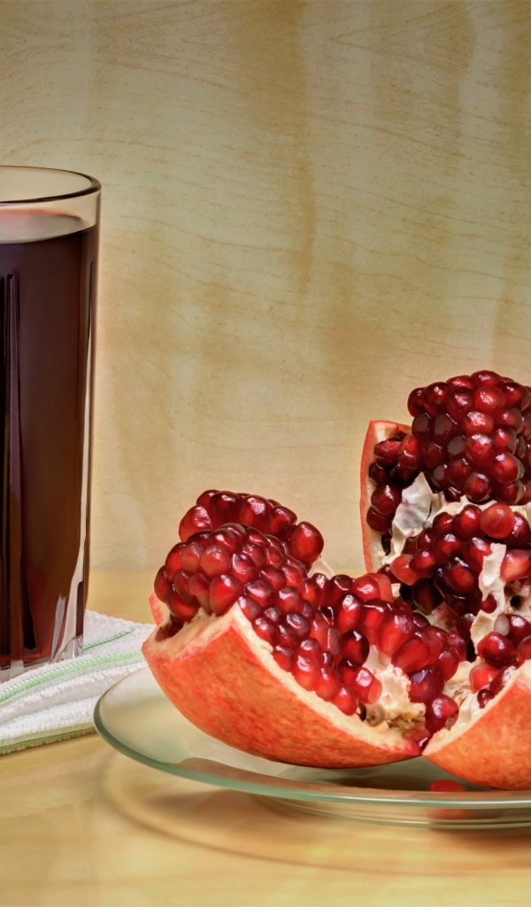 Красный гранат на столе со стаканом сока