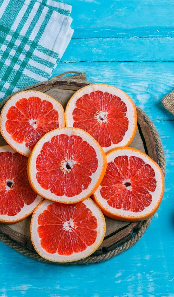 Нарезанный грейпфрут с соком на голубом столе