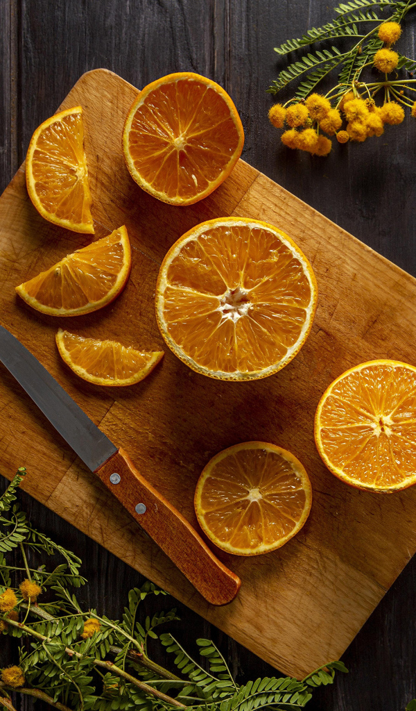 Нарезанный апельсин на доске на столе с цветами