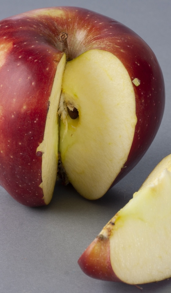 Разрезанное красное яблоко на сером фоне