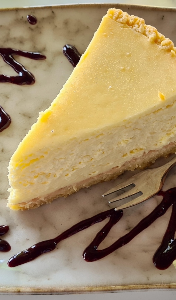 Кусок чизкейка с шоколадным топпингом на тарелке