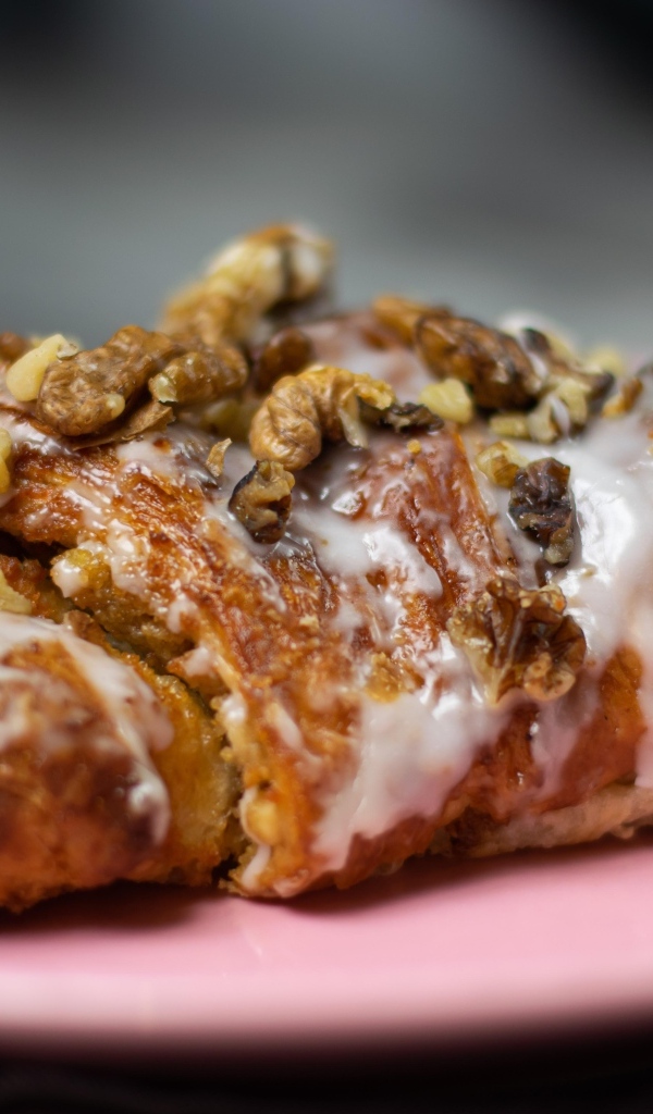 Круассан с кремом и грецкими орехами на розовой тарелке