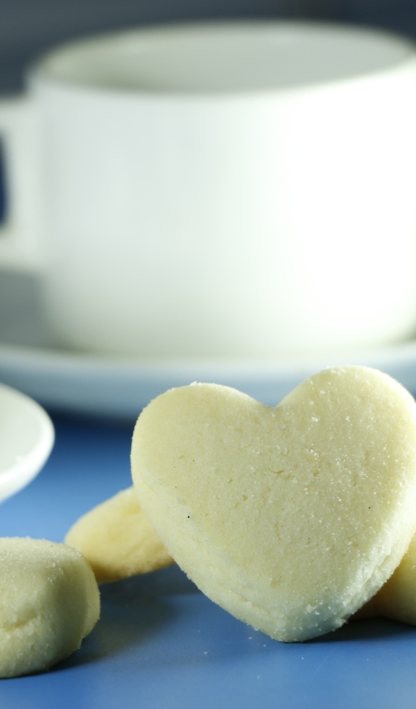 Сладкое печенье в форме сердца с кружками на столе