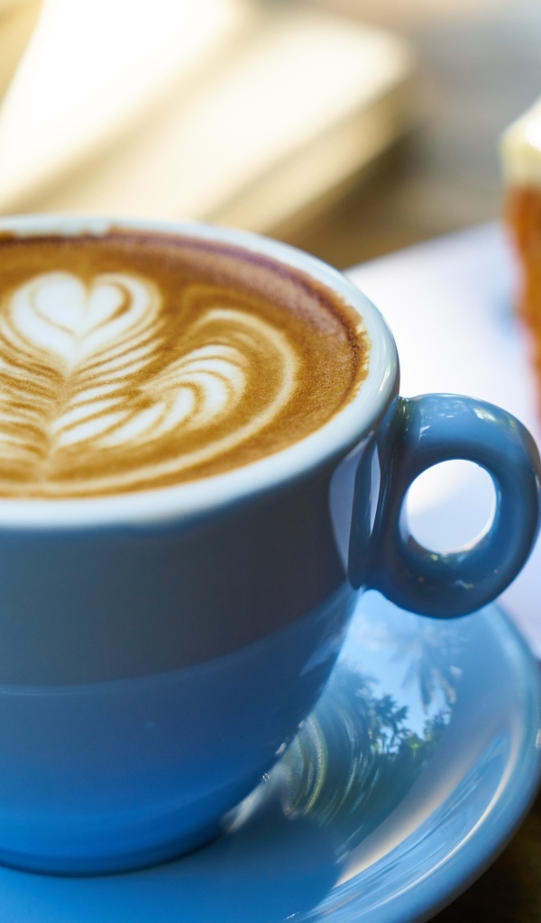 Чашка ароматного горячего кофе с рисунком на пене на столе на завтрак