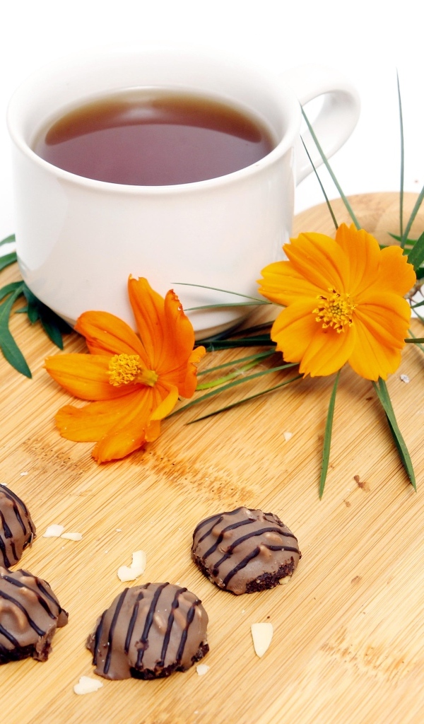 Чашка чая на деревянной доске с конфетами