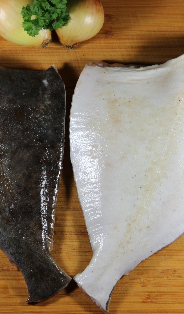 Камбала на доске с луком и ножом