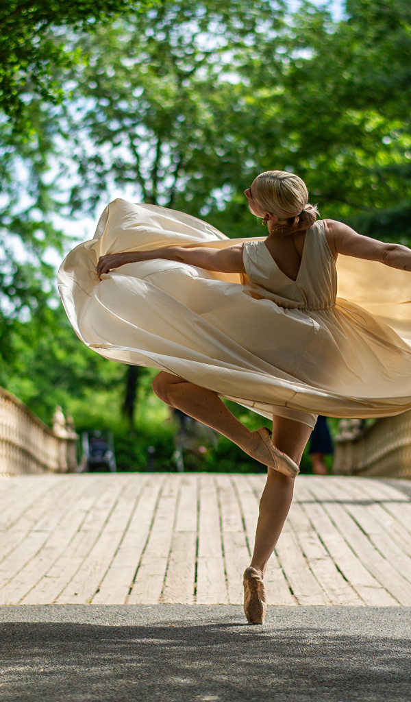 Девушка балерина в стойке на мосту