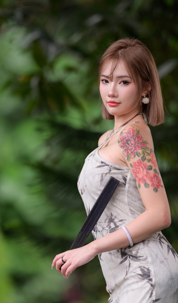 Красивая девушка азиатка с татуировкой на руке
