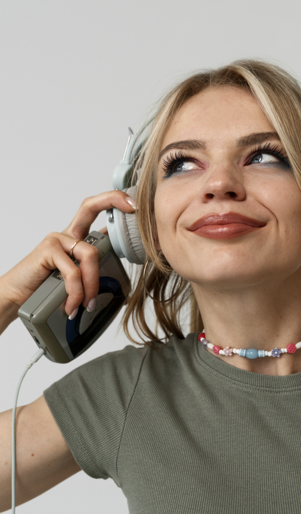 Красивая девушка в наушниках с плеером