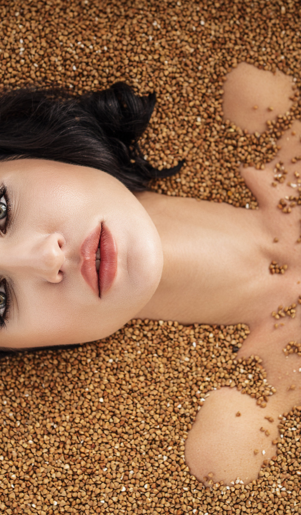 Красивая девушка лежит в зернах гречки