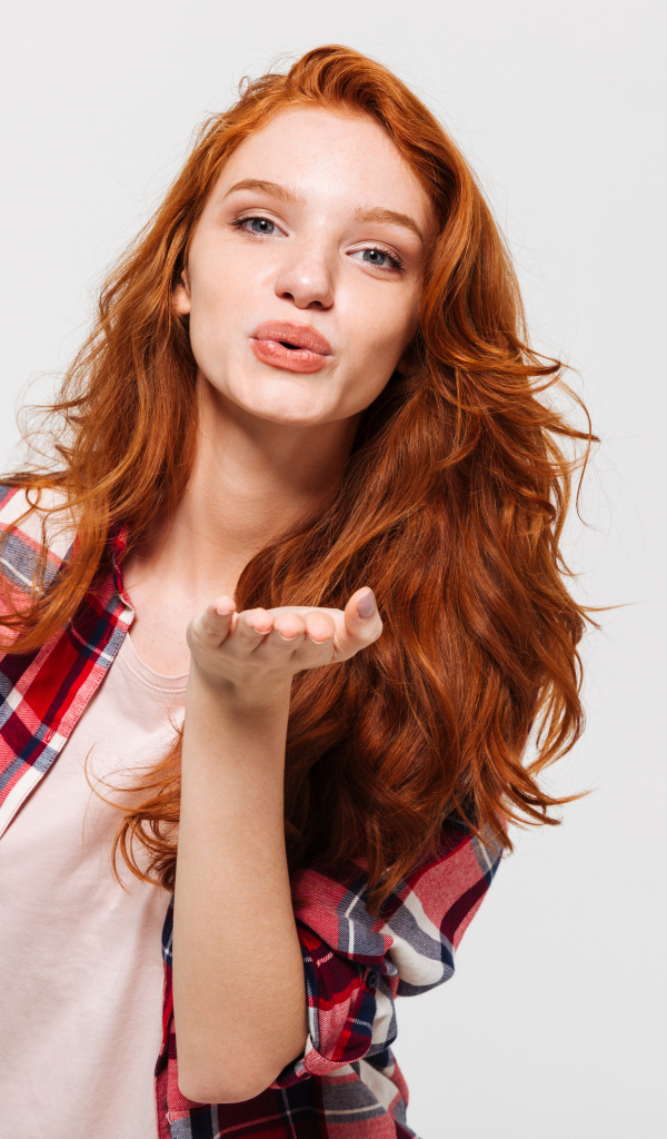 Красивая рыжеволосая девушка шлет воздушный поцелуй