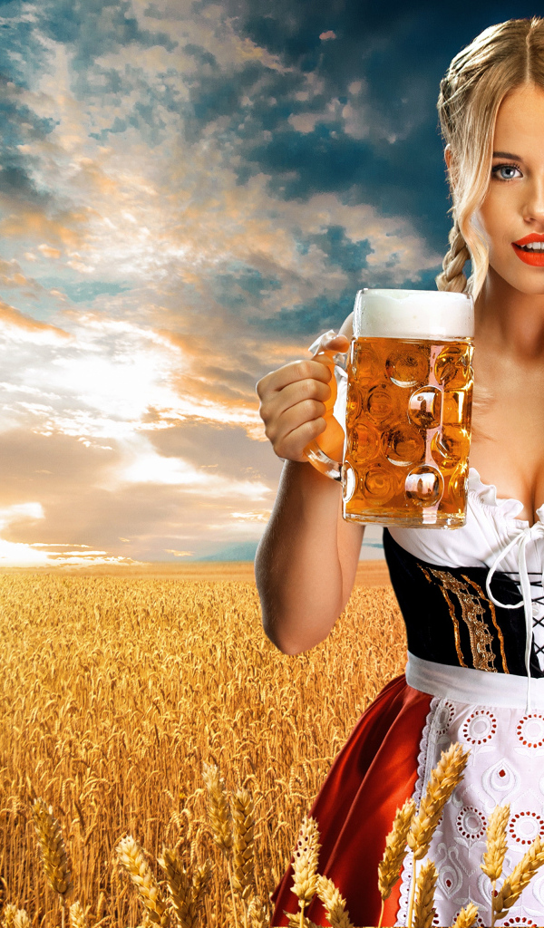 Девушка немка с бокалом пива на поле с пшеницей