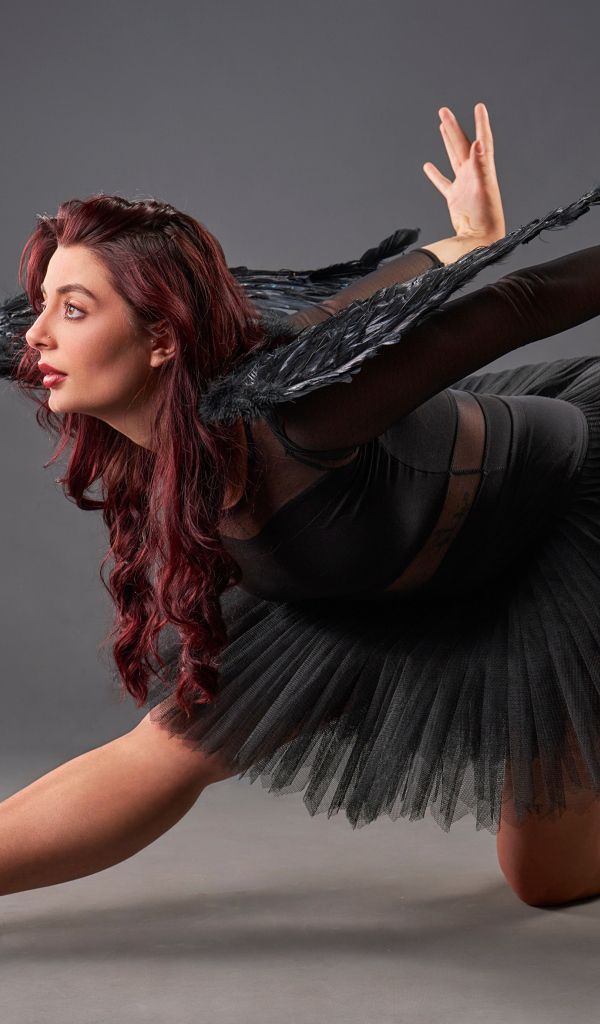 Девушка в черном костюме с крыльями танцует
