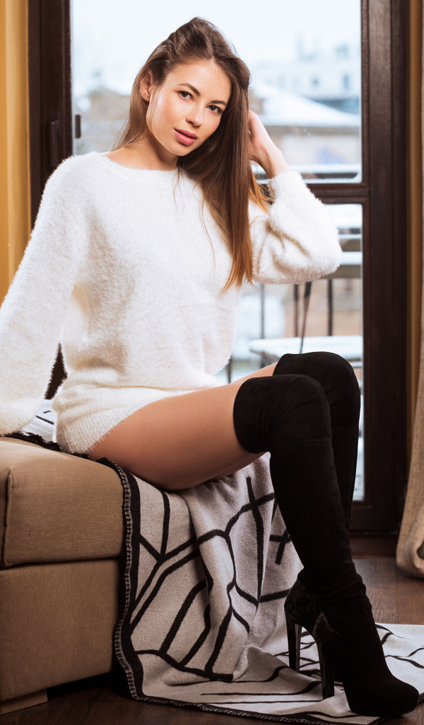 Девушка в белом свитере и высоких черных сапогах 