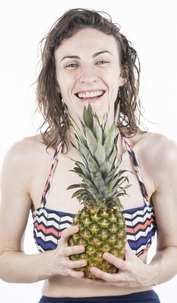 Улыбающаяся девушка с ананасом в руках