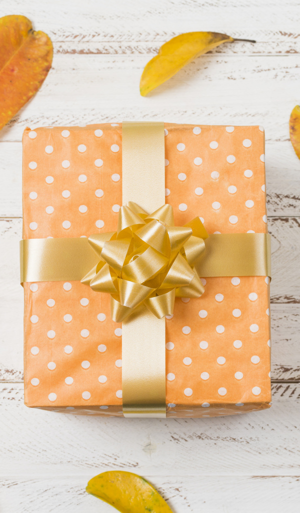 Подарок с желтыми листьями на белом фоне