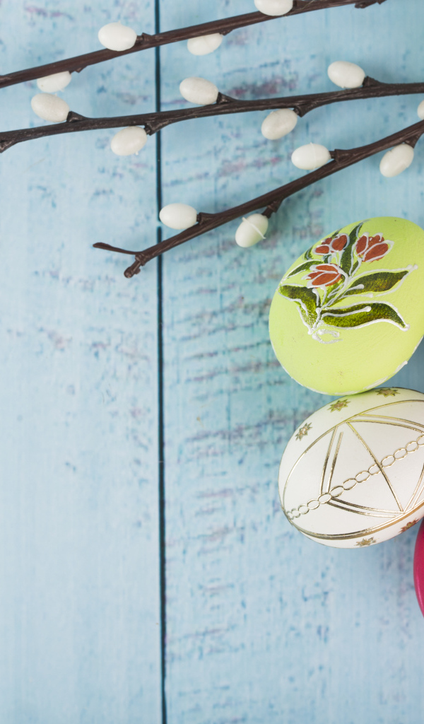 Красивые пасхальные яйца с ветками вербы и цветами хризантемы на голубом фоне