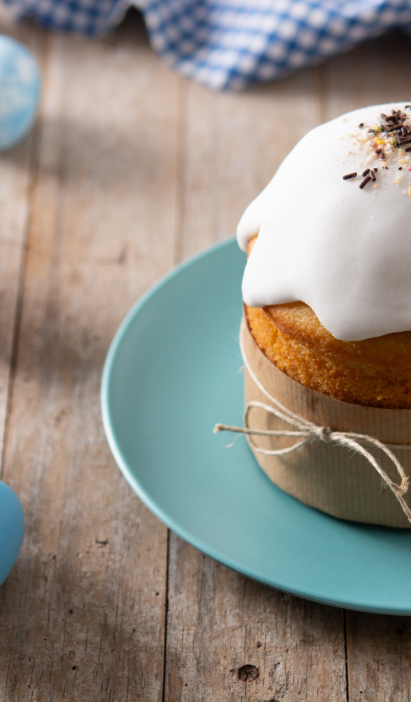 Кулич с крашеными яйцами и цветами на столе на Пасху