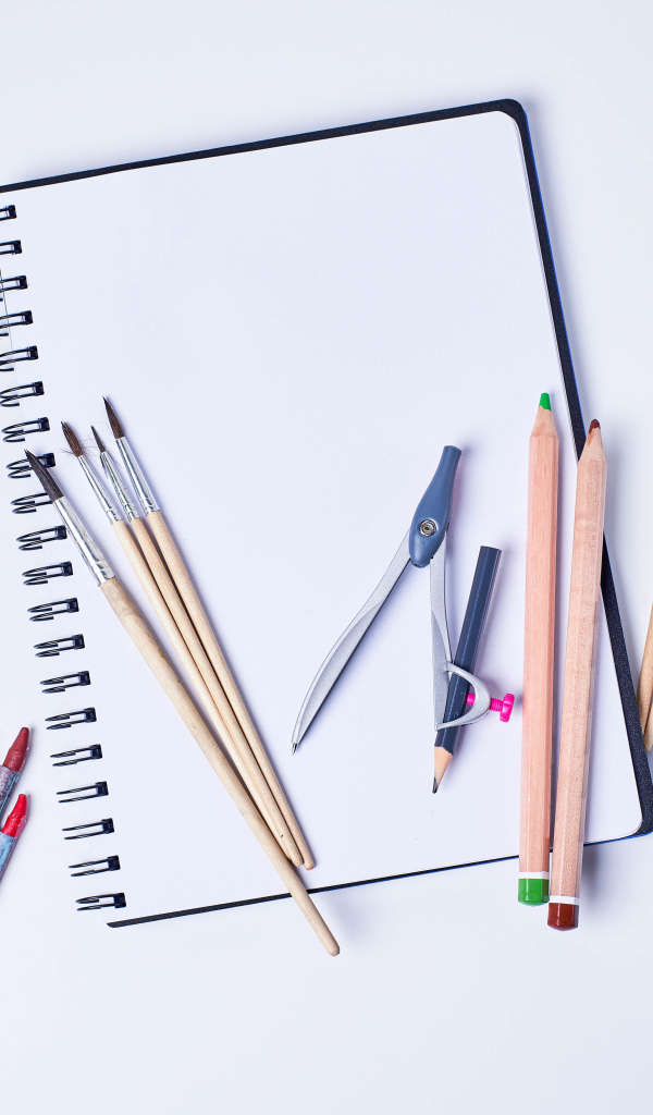 Карандаши, кисти и блокнот для рисования на сером фоне