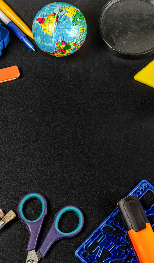 Канцелярские предметы, глобус и игрушечный автобус на черном фоне