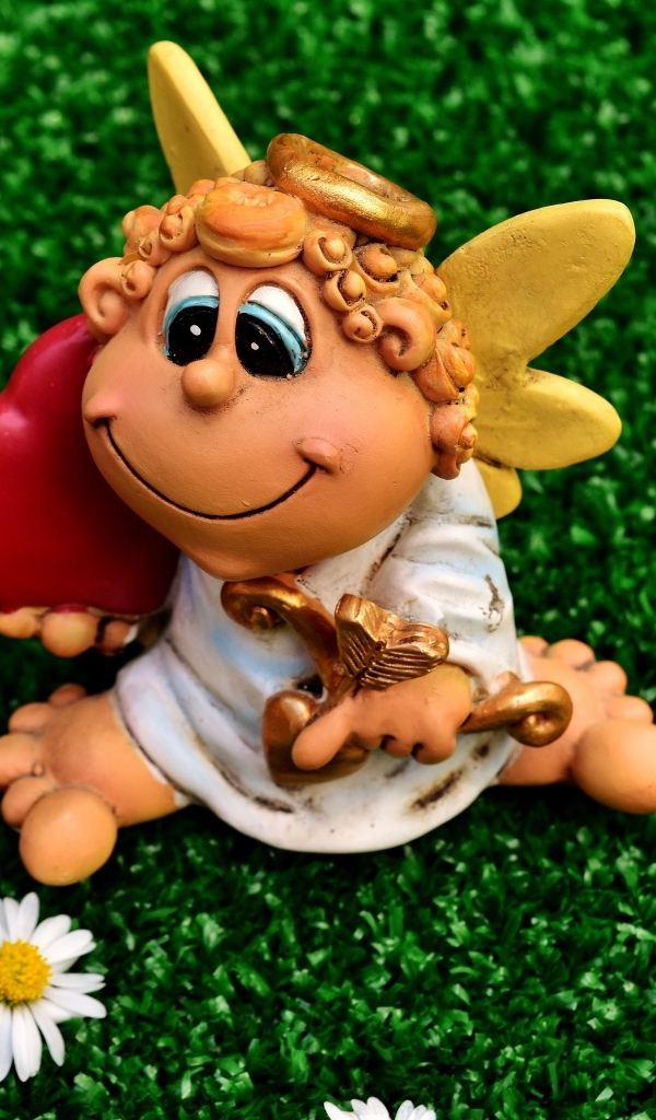 Статуэтка ангела на зеленой траве с белыми ромашками