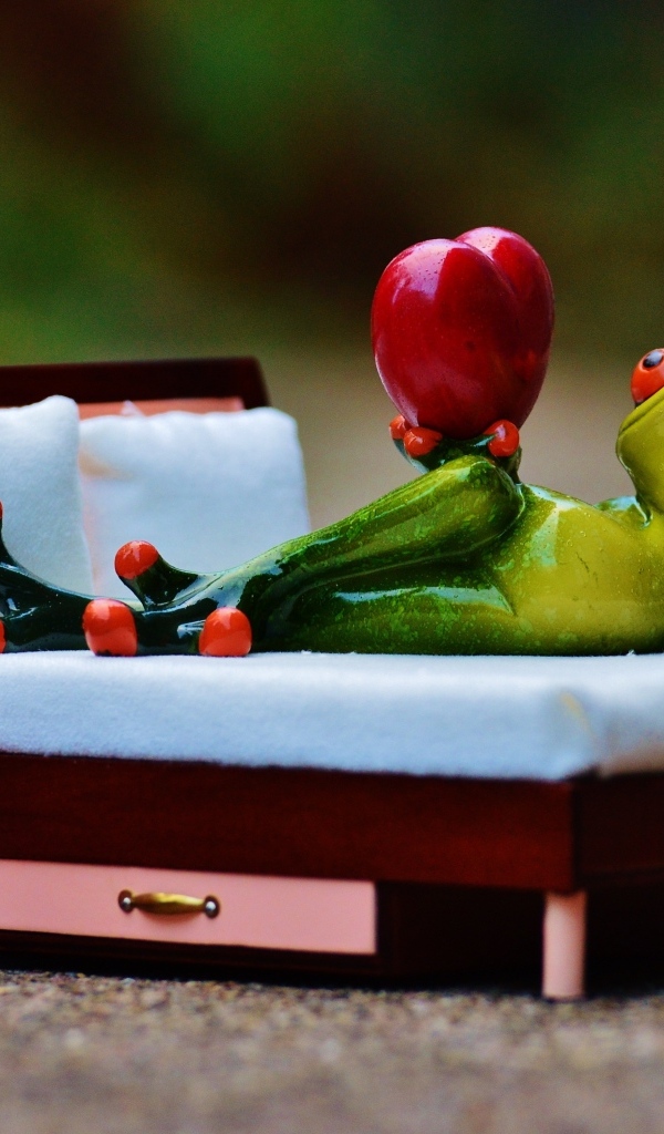 Фигурка зеленая лягушка с красным сердцем на кровати