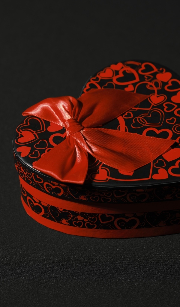 Шкатулка в форме сердца с красным бантом на черном фоне
