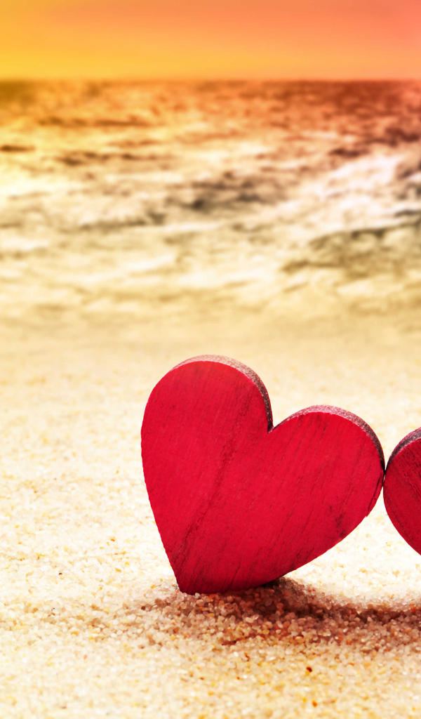 Два красных сердечка на песке на пляже