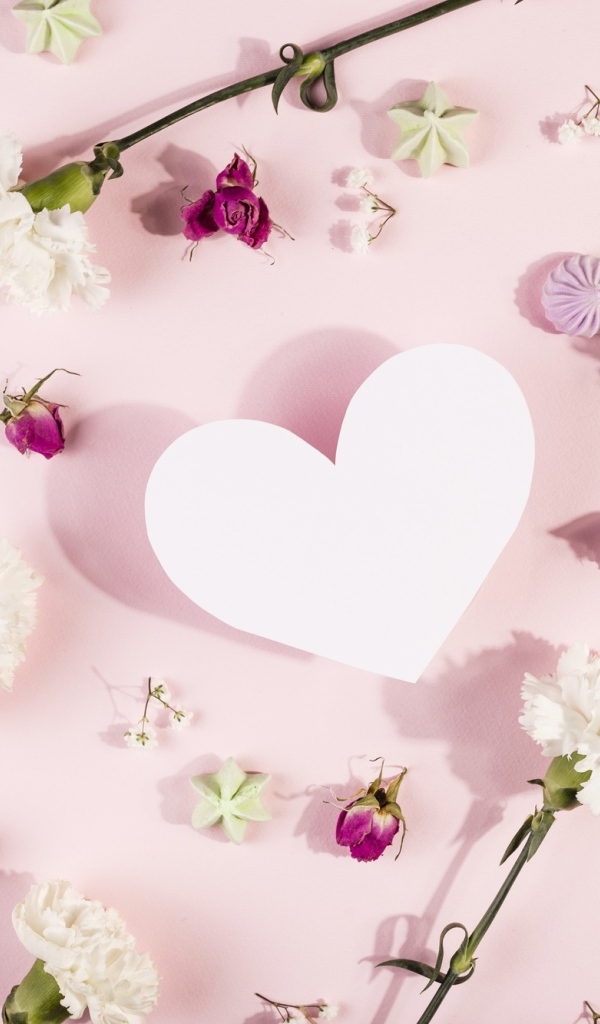 Белое бумажное сердце на розовом фоне с цветами