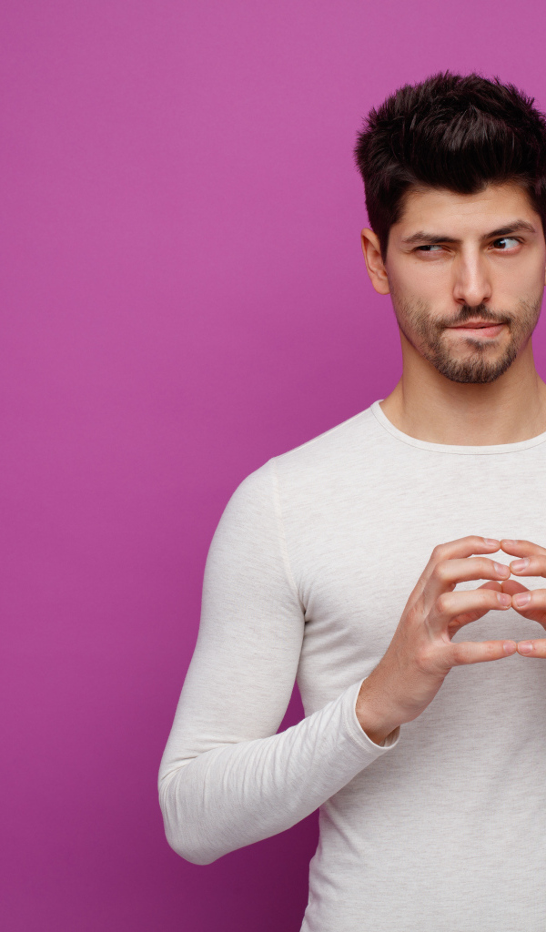 Хитрый мужчина в белом свитере на сиреневом фоне