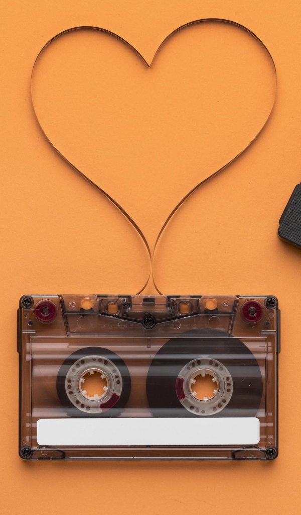 Кассеты и сердце из ленты на оранжевом фоне