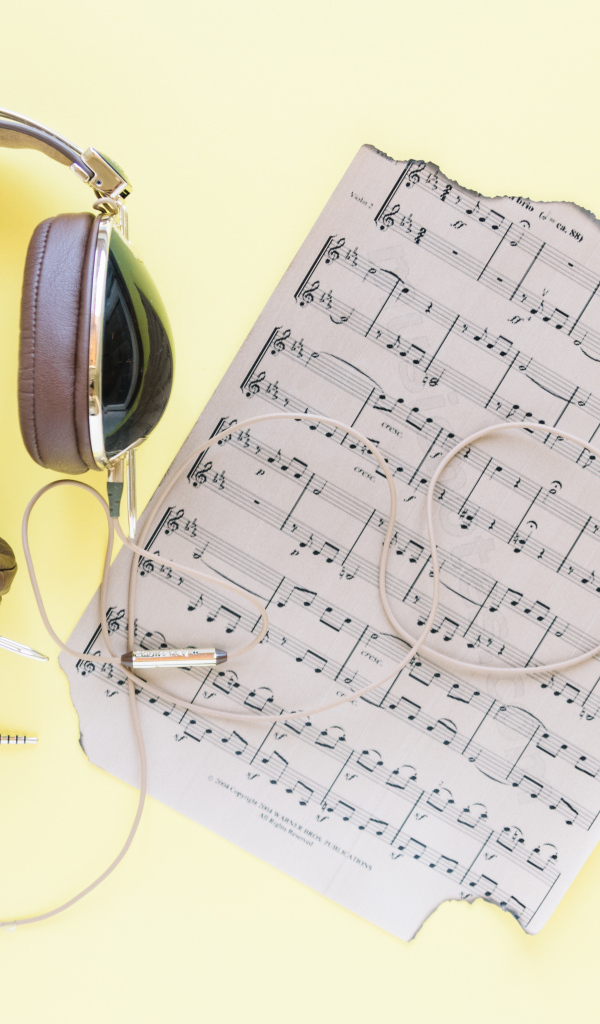 Старые ноты и наушники на желтом фоне