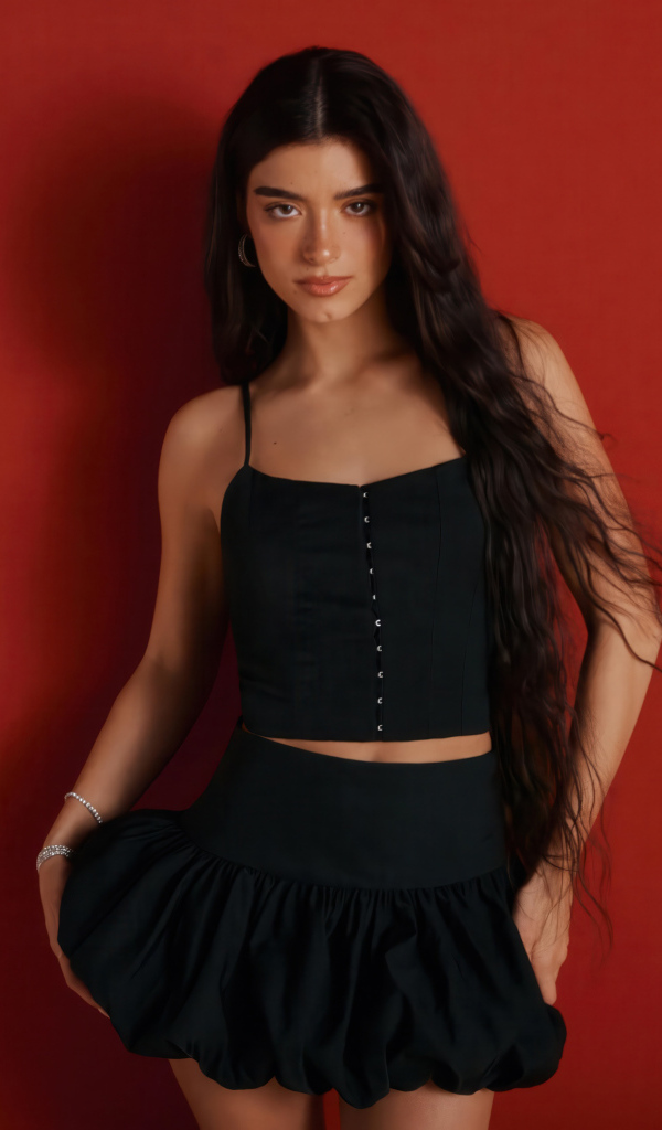 Популярная девушка Дикси Дамелио в черном костюме на красном фоне