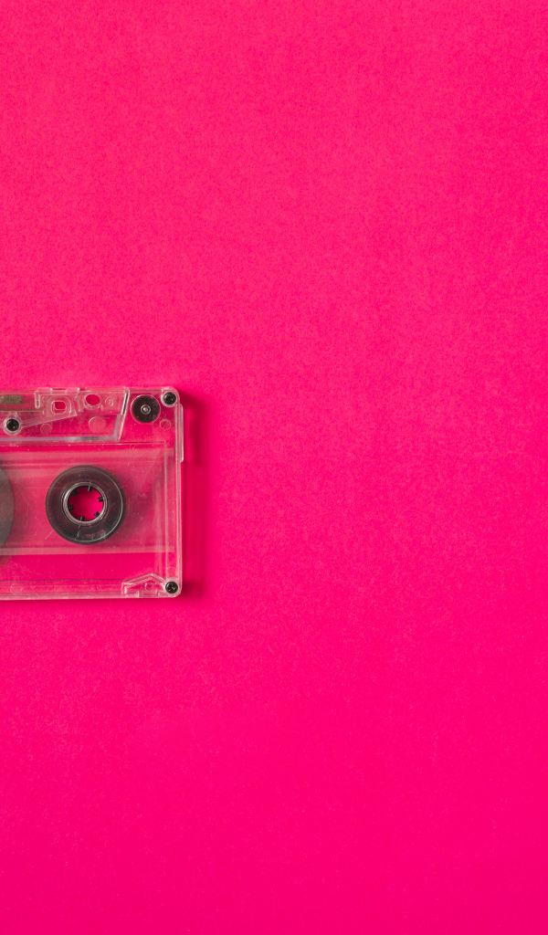 Маленькая магнитофонная кассета на розовом фоне